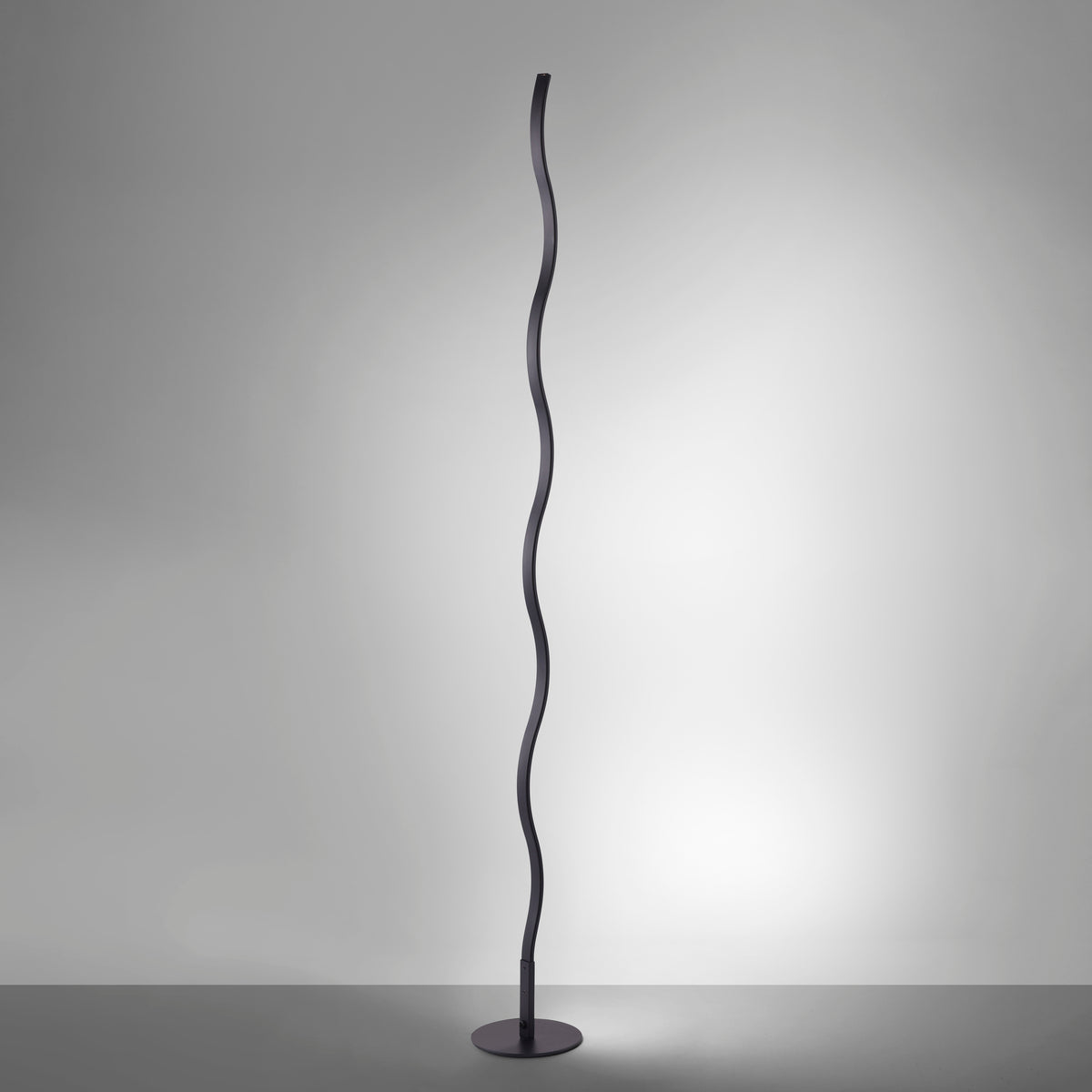 Lampadaire allumé dans une pièce sombre, halo lumineux diffusé par le ruban ondulé noir.