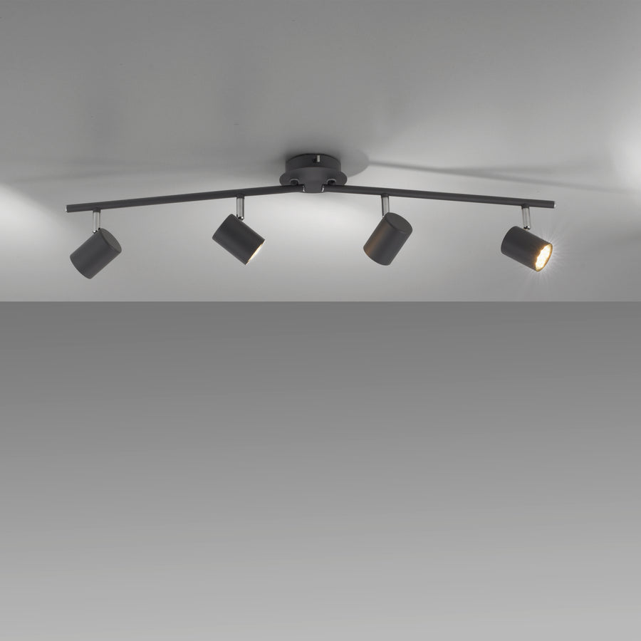 Luminaire allumé au plafond, quatre spots orientables créant des jeux d'ombres.