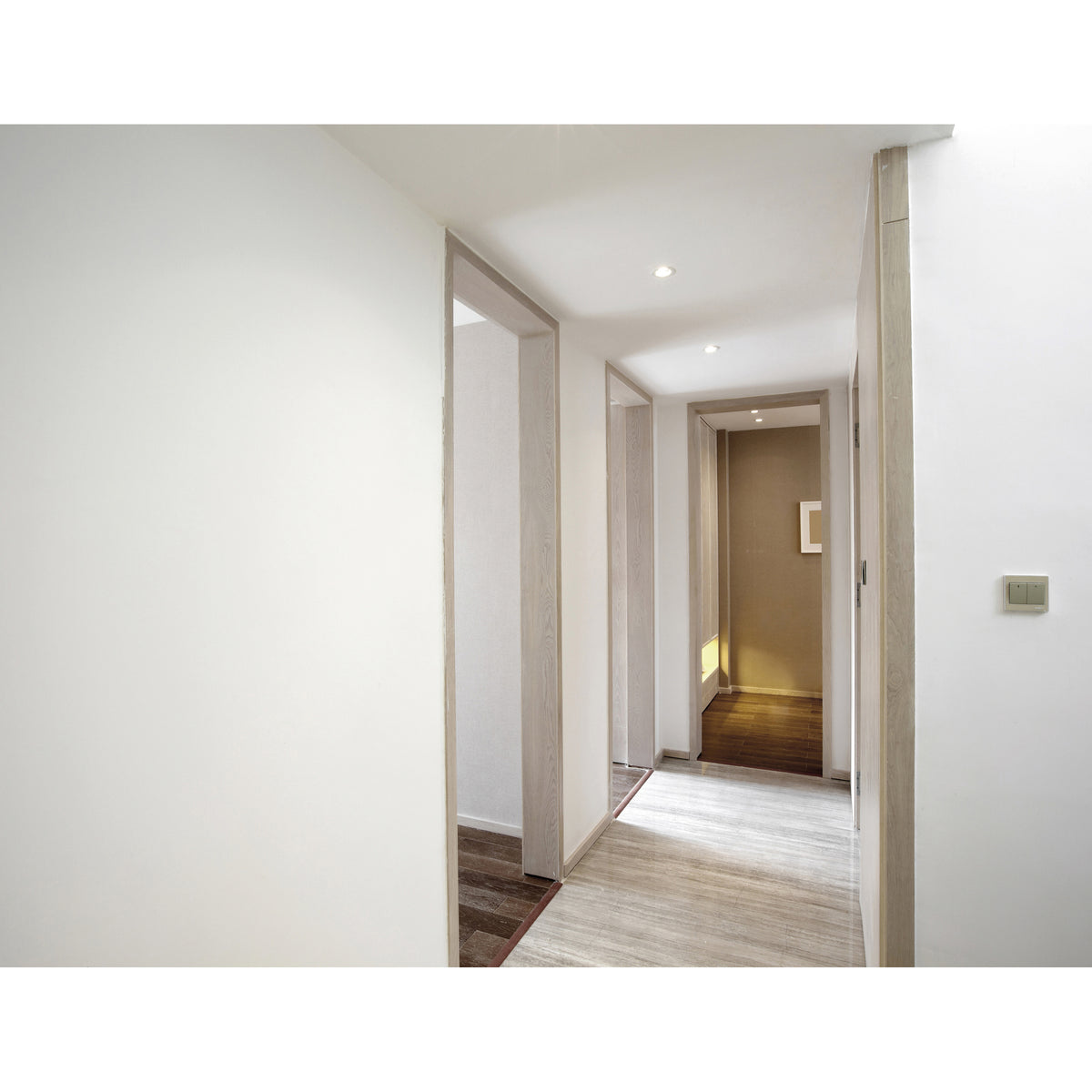 Couloir moderne éclairé par plusieurs spots encastrés au plafond blanc.
