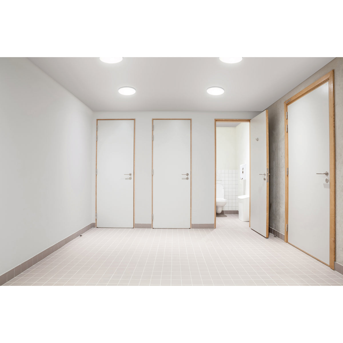 Mise en situation dans un couloir sanitaire, plusieurs plafonniers allumés au plafond.