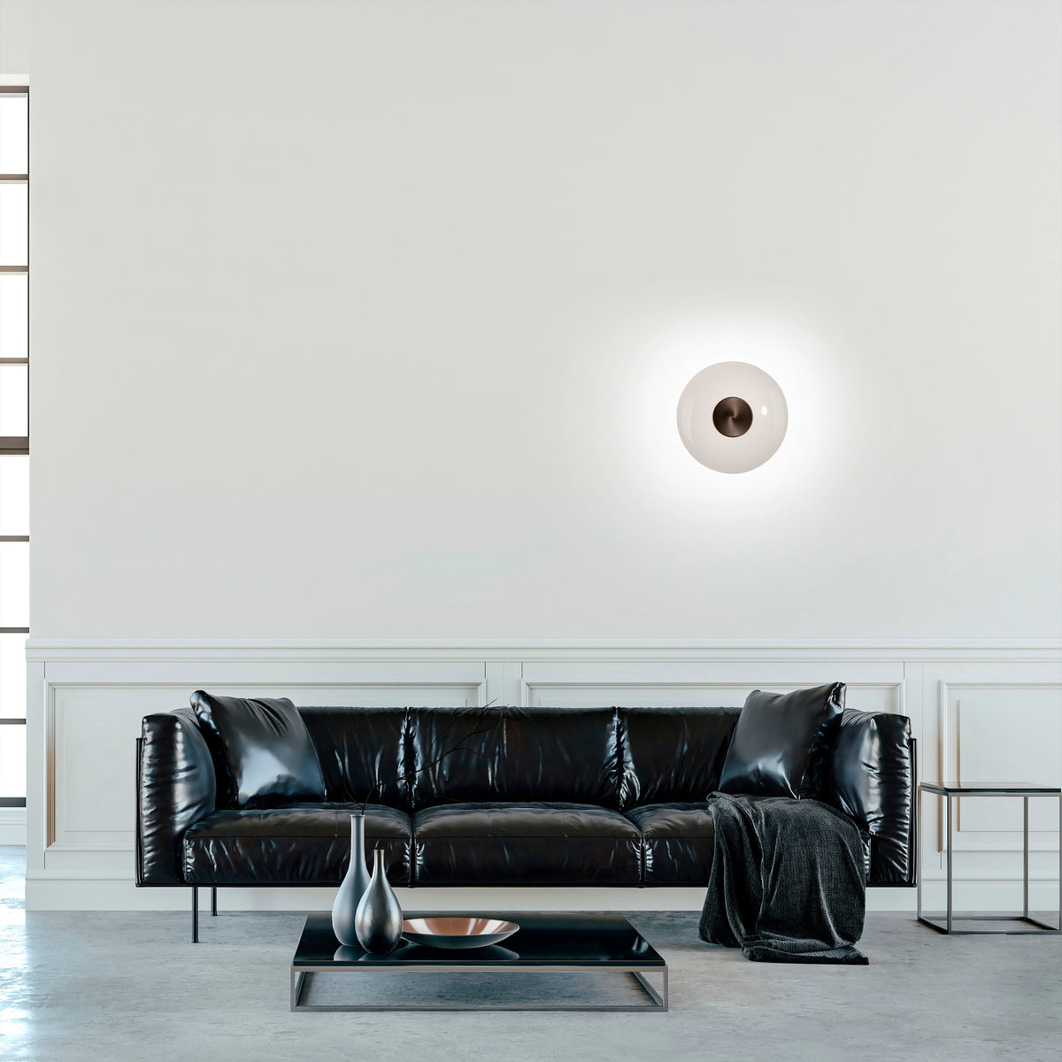 Mise en ambiance dans un salon, applique murale allumée éclairant un mur blanc.