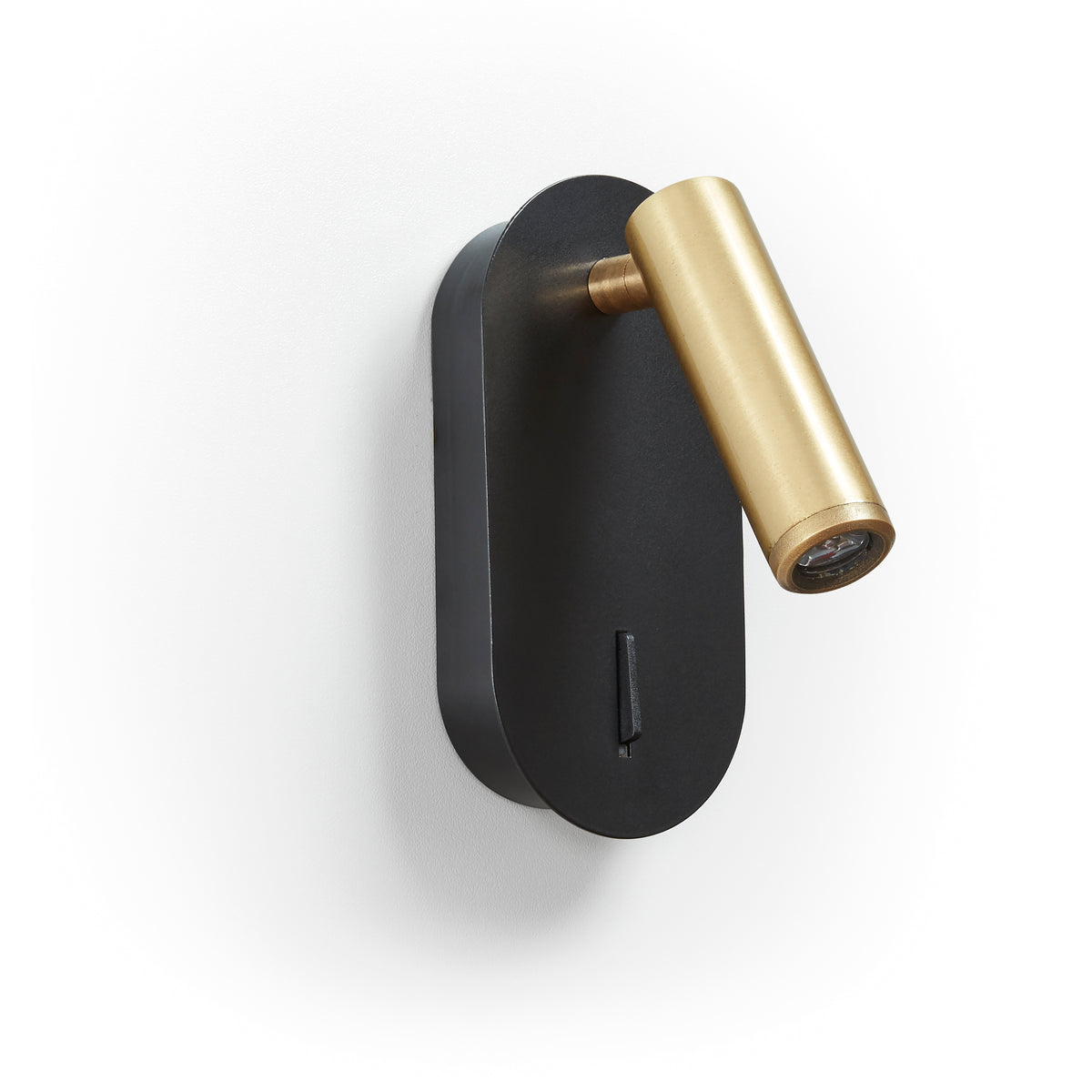 Détail finition : socle noir ovale et projecteur cylindrique en laiton brossé orientable.