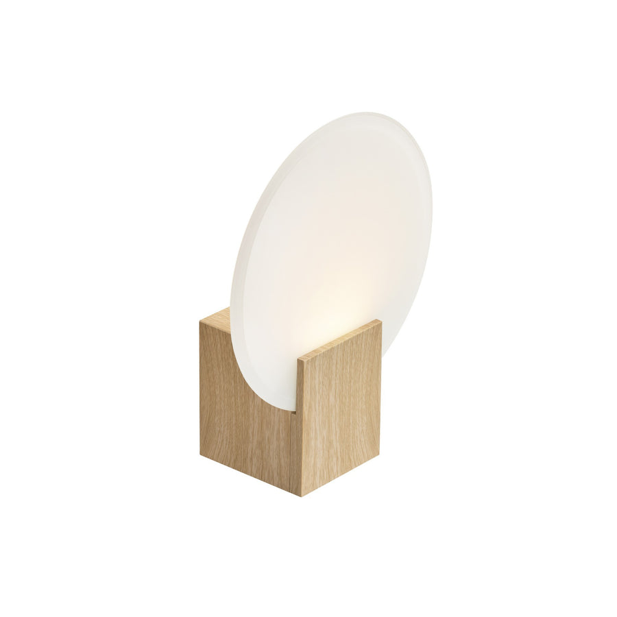 Vue de trois quarts du luminaire mural à base en bois clair et disque en verre
