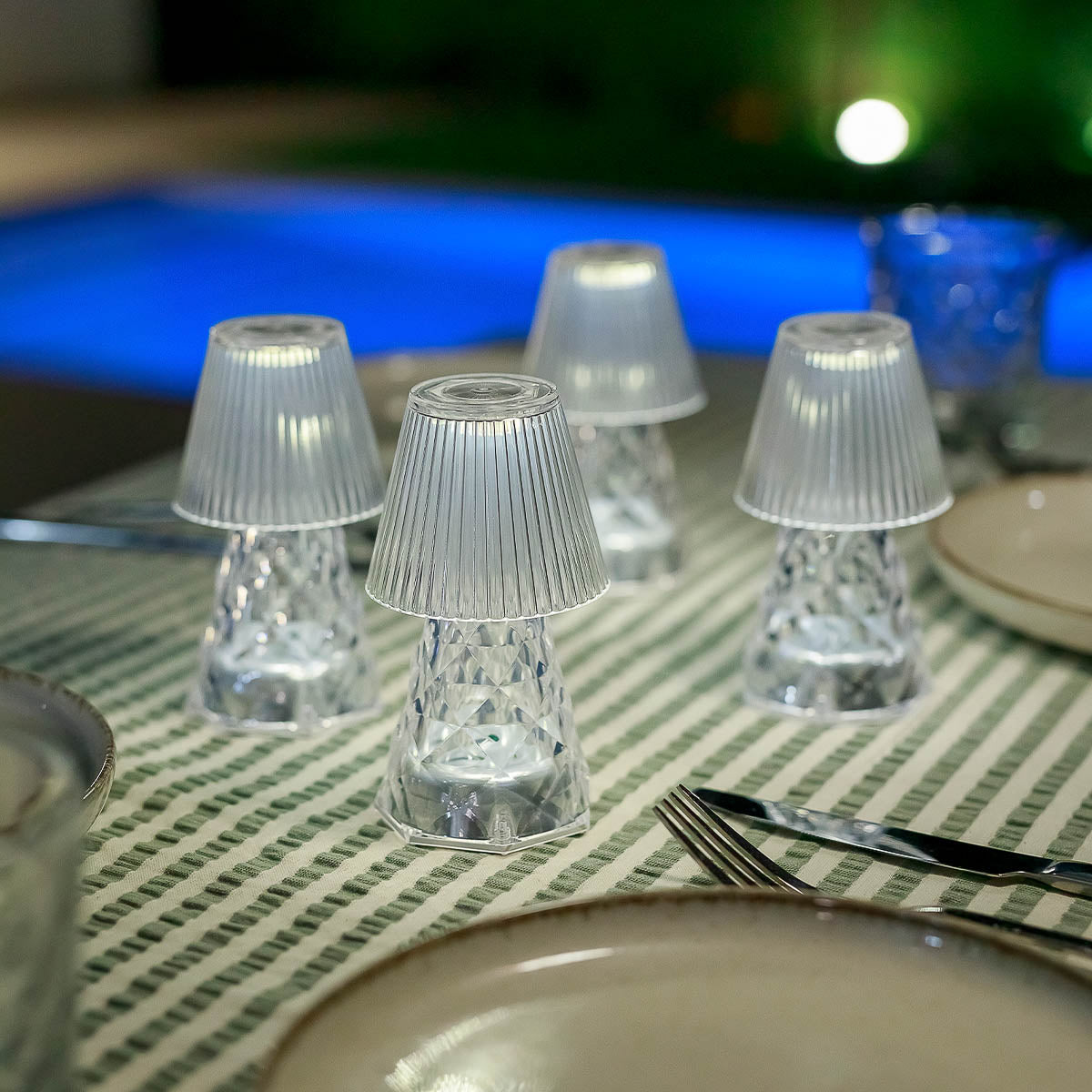 Plusieurs lampes transparentes allumées posées sur une nappe rayée pendant un dîner