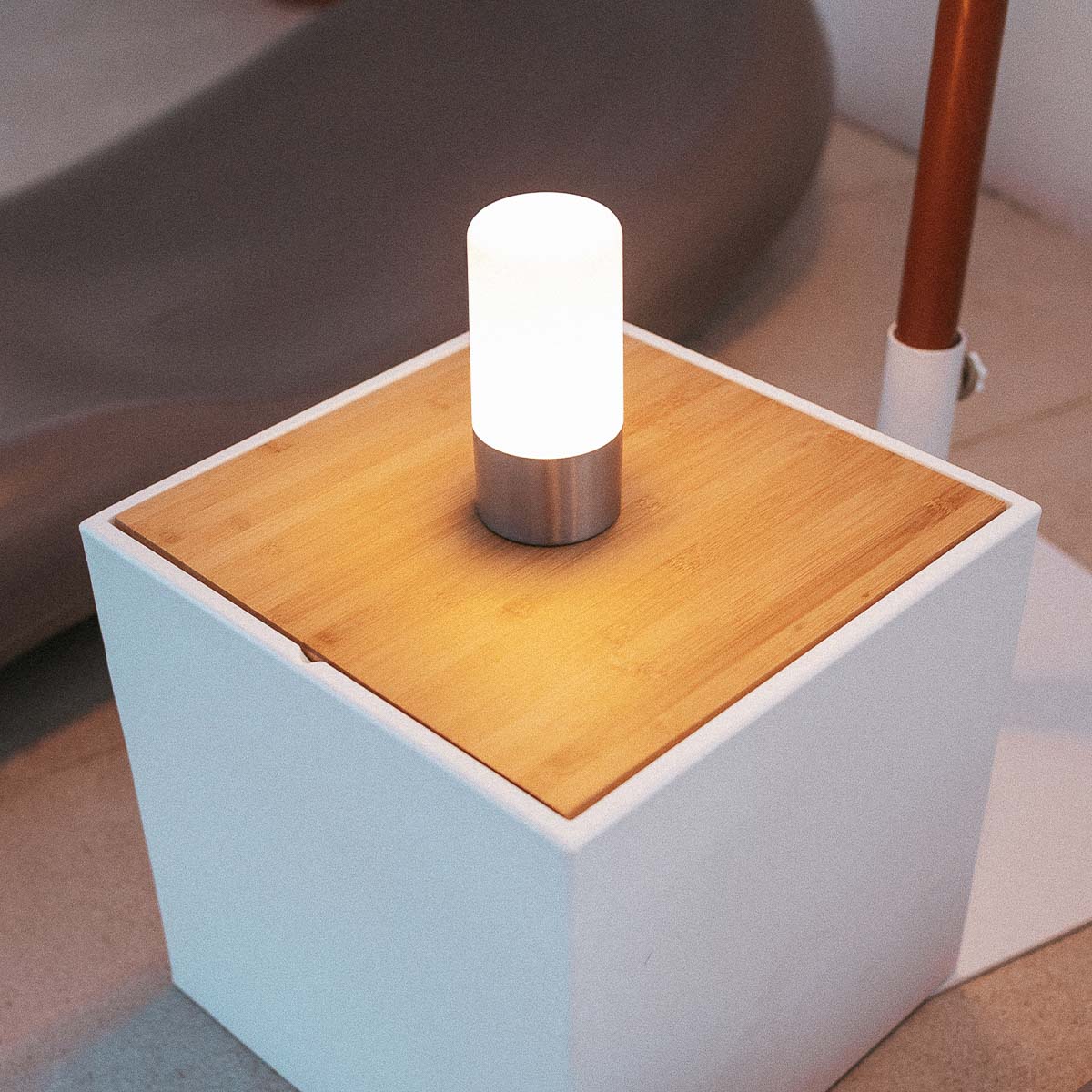 Mise en ambiance sur une table en bambou près d'un canapé, lumière diffuse allumée.