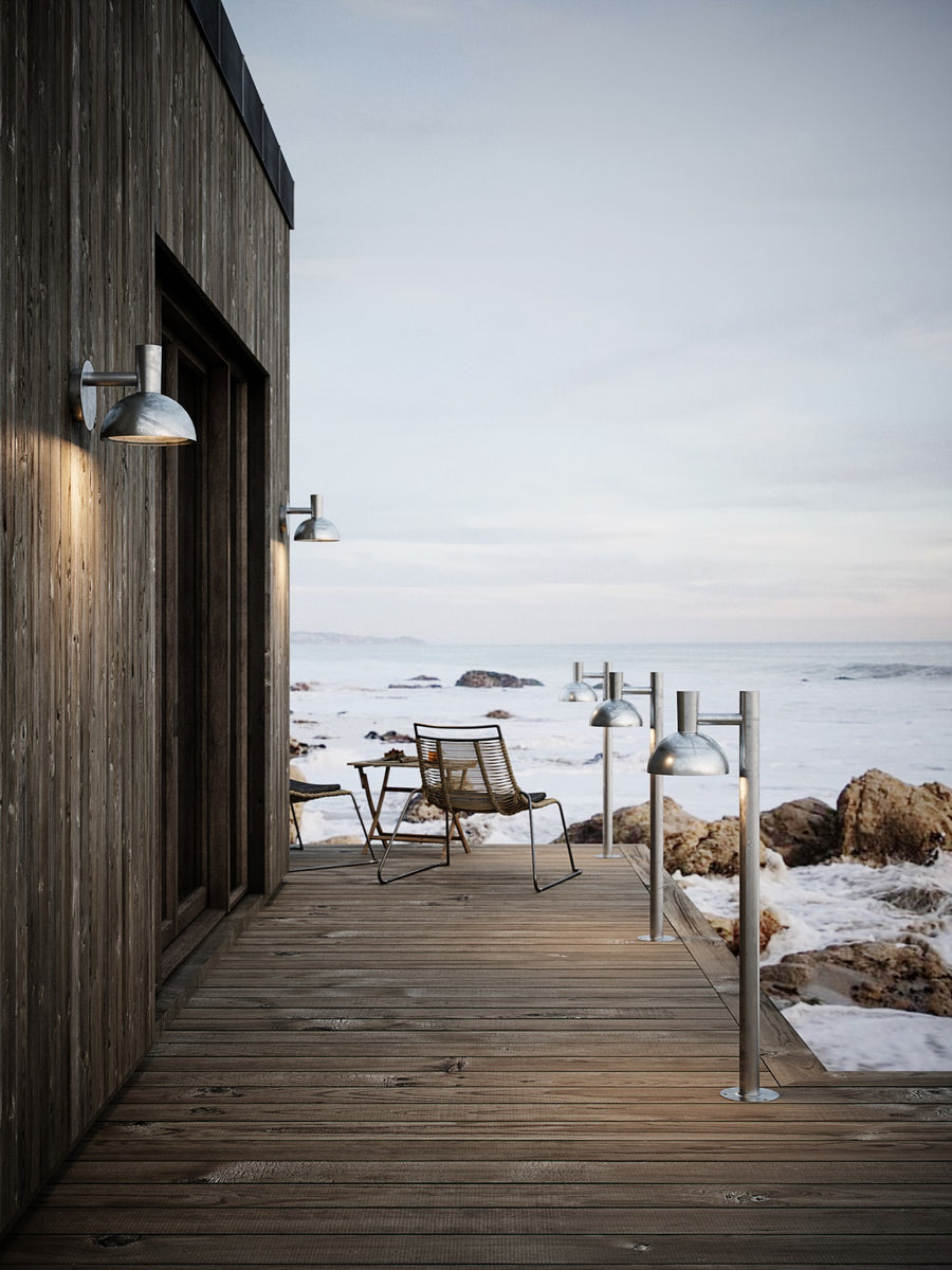 Mise en scène extérieure avec appliques et bornes lumineuses sur une terrasse en bois.