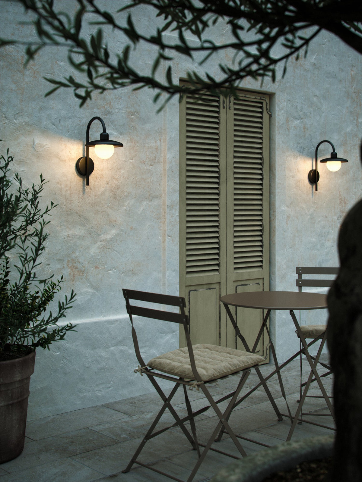 Mise en ambiance nocturne sur une terrasse, deux appliques murales éclairant un mur texturé.