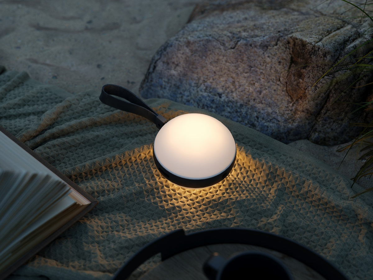 Mise en ambiance nocturne, lampe posée sur plaid texturé près d'un livre.