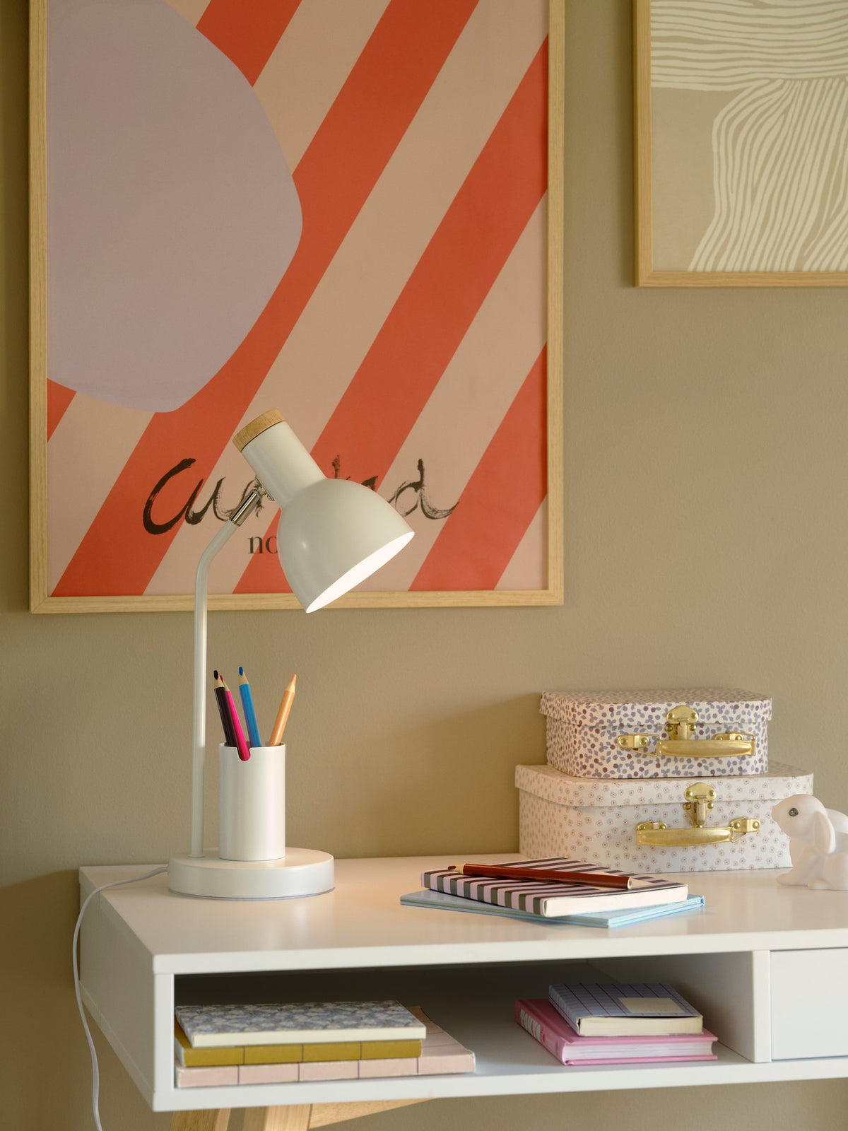 Mise en ambiance sur un bureau blanc, lampe allumée près d'un pot à crayons