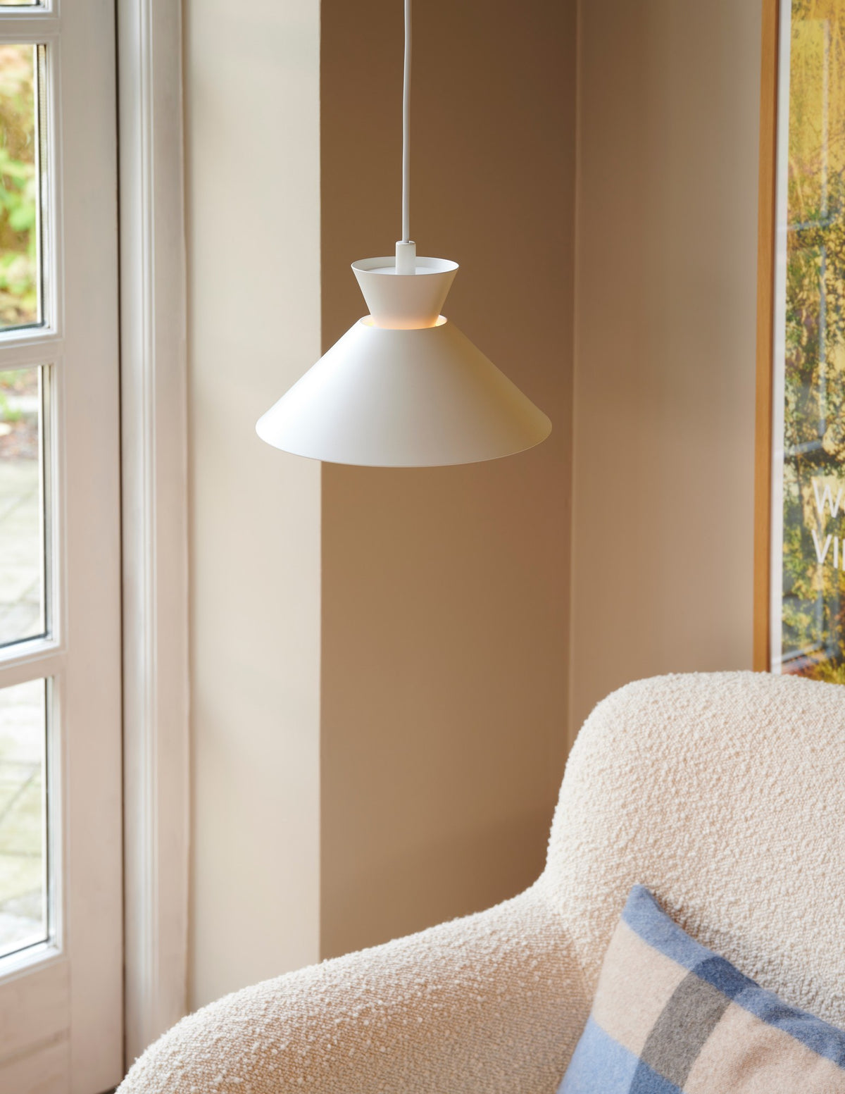 Mise en ambiance dans un salon beige avec fauteuil bouclé et fenêtre.