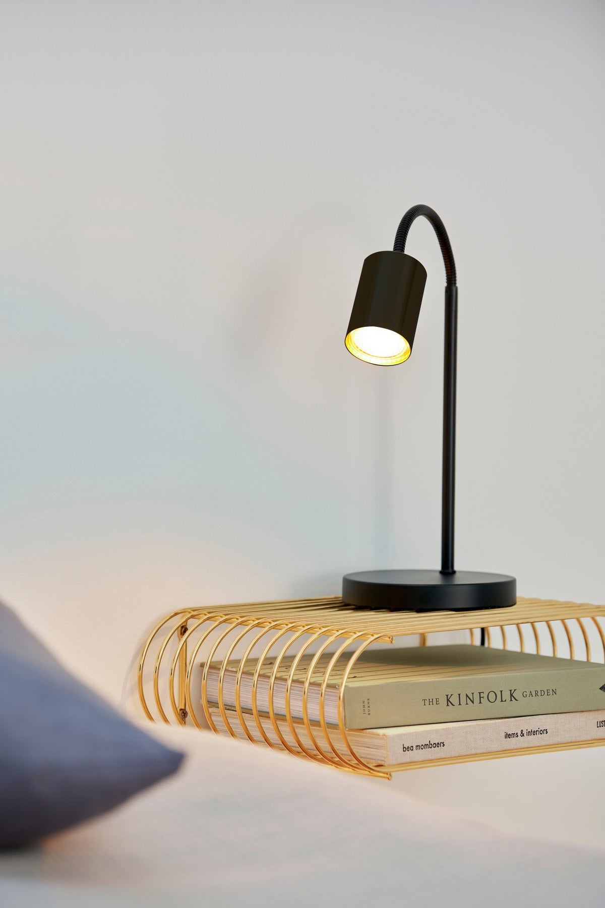 Mise en ambiance sur une table de chevet, lampe allumée près de livres.