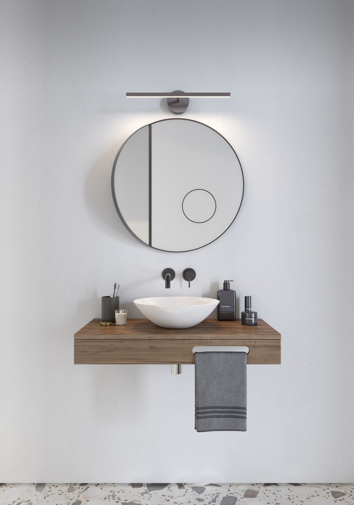 Mise en ambiance salle de bain : applique fixée au-dessus d'un miroir rond et d'une vasque sur plan bois
