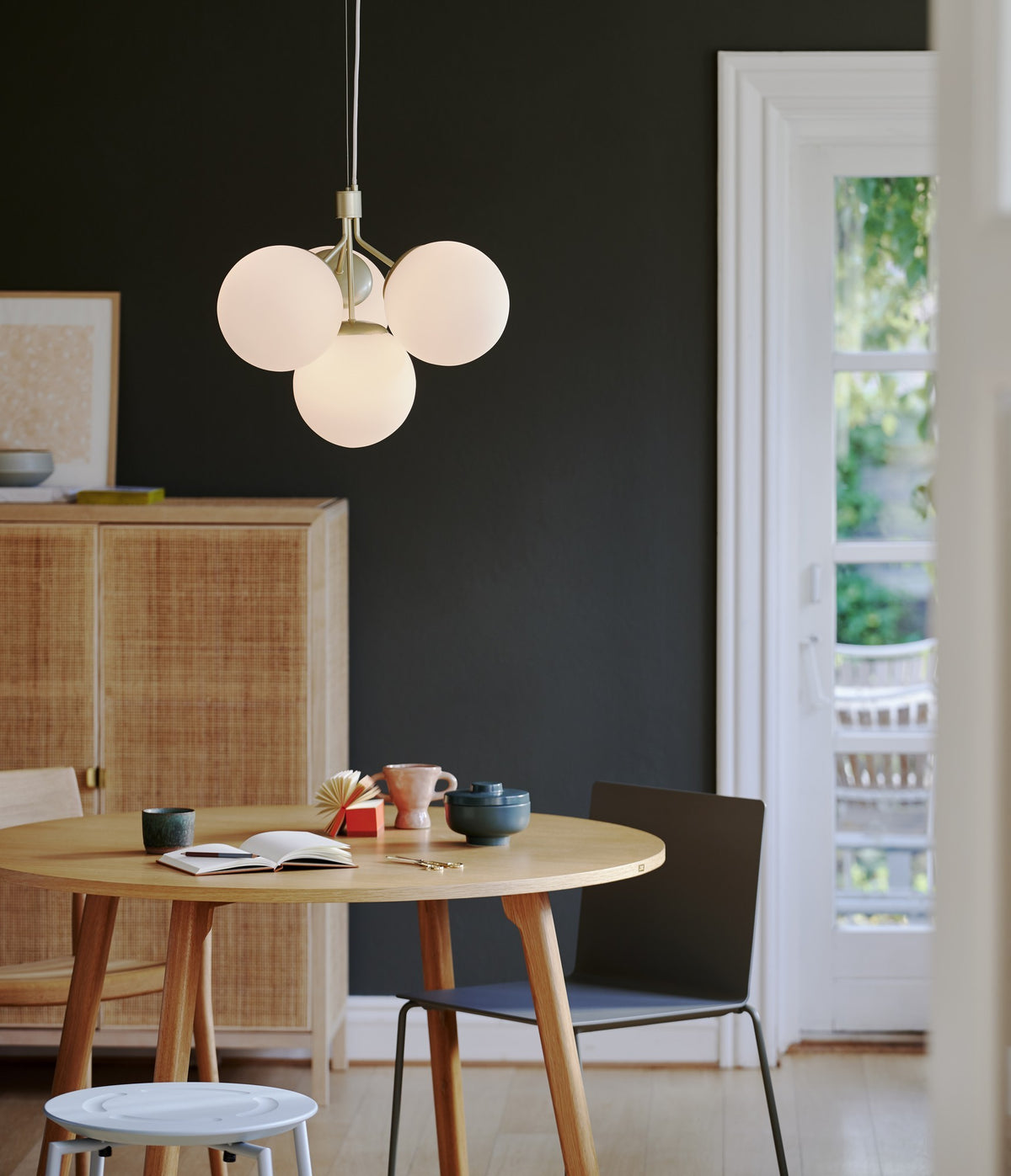 Mise en ambiance : suspension allumée au-dessus d'une table ronde dans un intérieur contemporain.