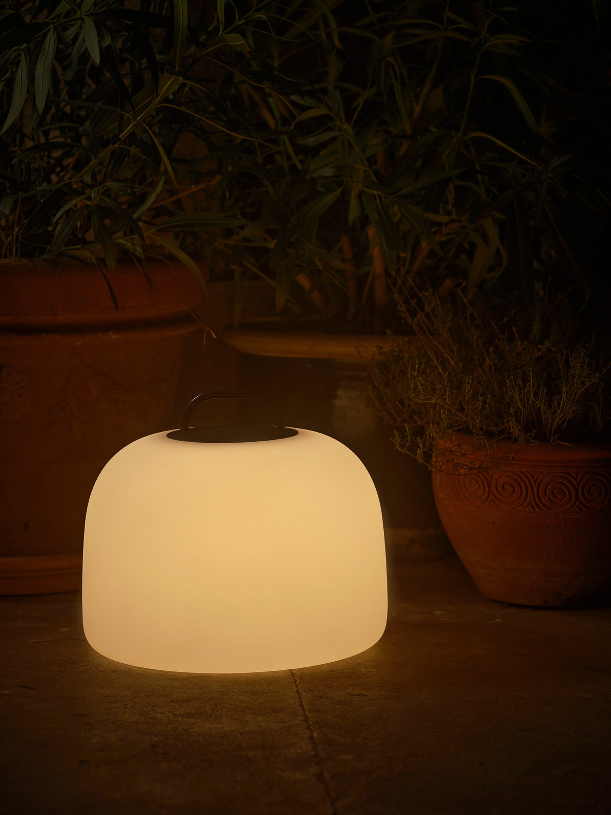 Mise en ambiance nocturne, lampe posée au sol près de pots de terre cuite