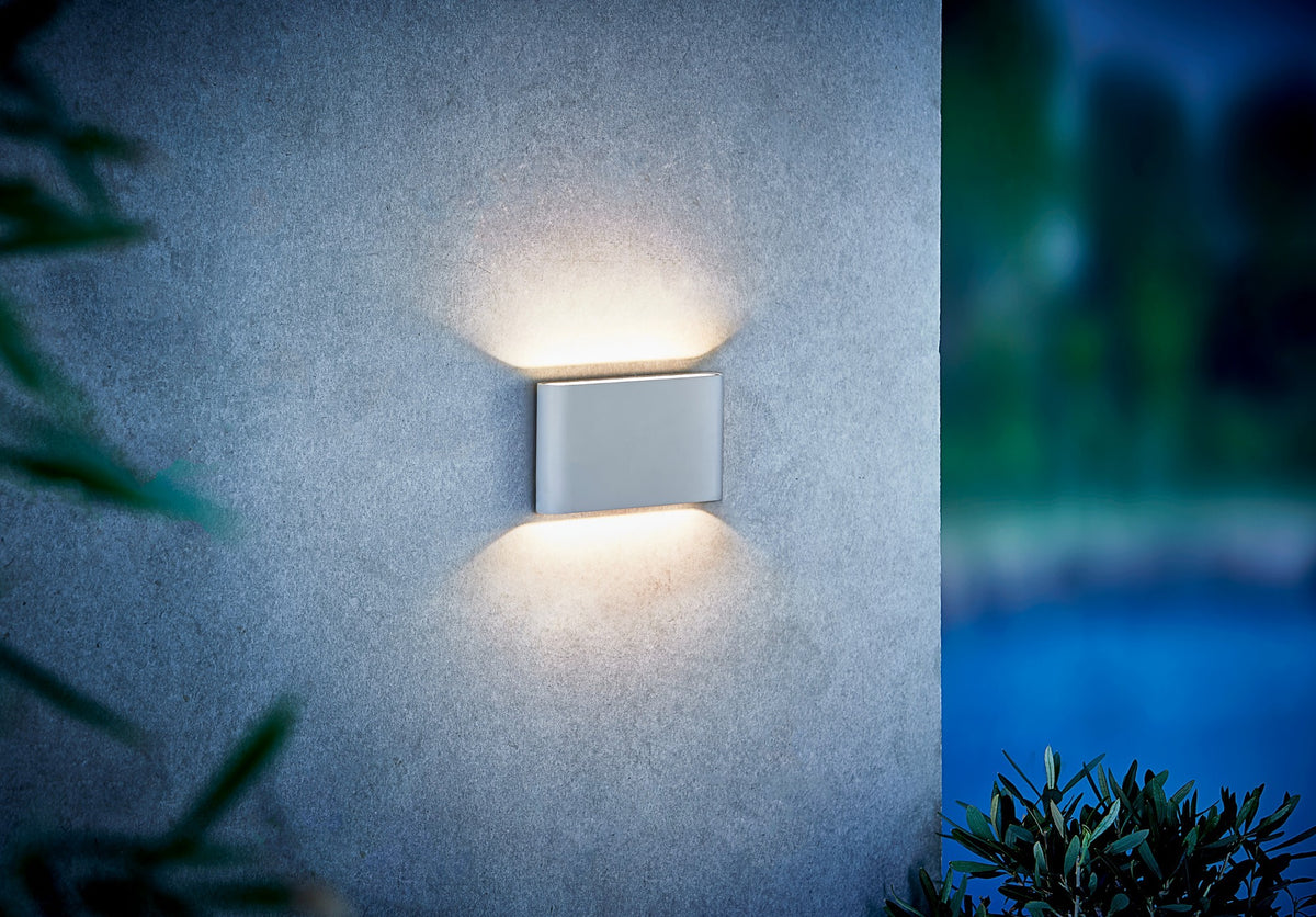 Mise en ambiance nocturne d'une applique blanche éclairant un mur extérieur en béton