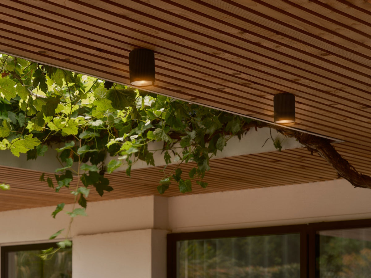 Mise en ambiance sous une pergola en bois avec deux plafonniers allumés