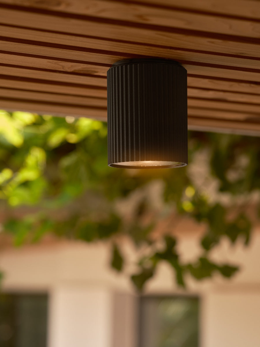 Gros plan du plafonnier fixé au plafond bois dans un jardin