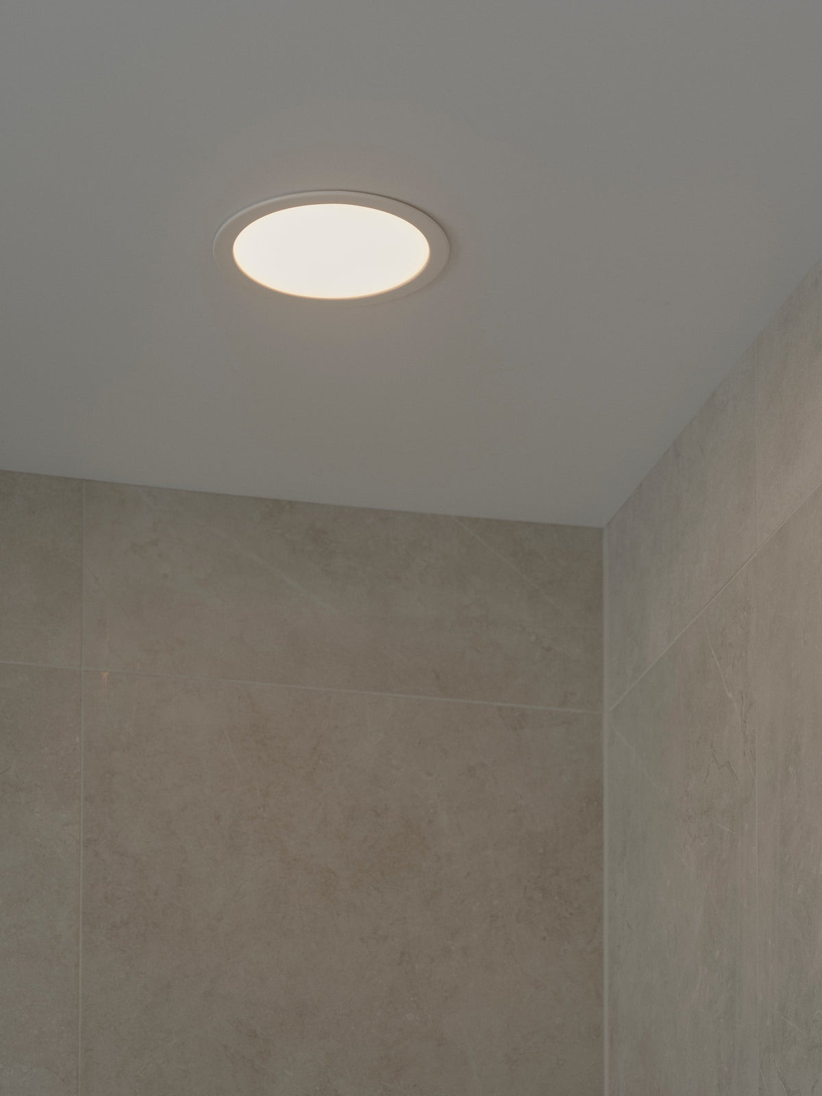 Mise en ambiance d'un spot encastré au plafond dans une salle de bain carrelée