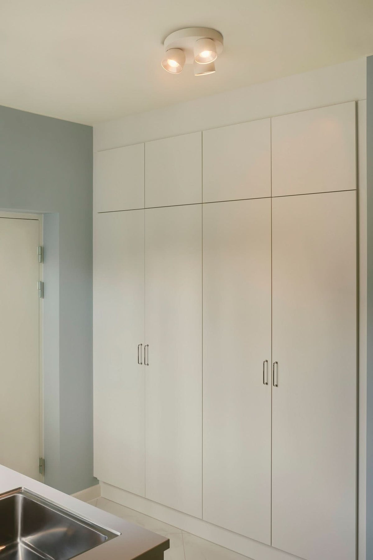 Mise en situation dans une pièce avec placards blancs, luminaire fixé au plafond