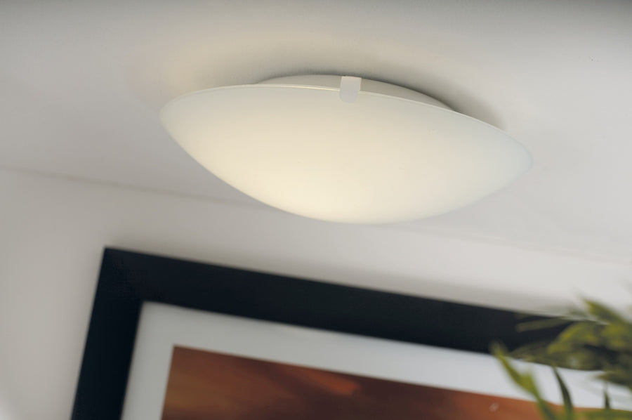 Plafonnier blanc allumé, fixé au plafond, diffusant une lumière douce dans une pièce.
