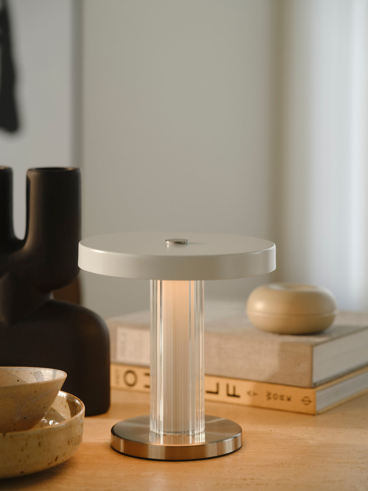 Mise en ambiance sur un meuble, lampe allumée près de livres et objets décoratifs