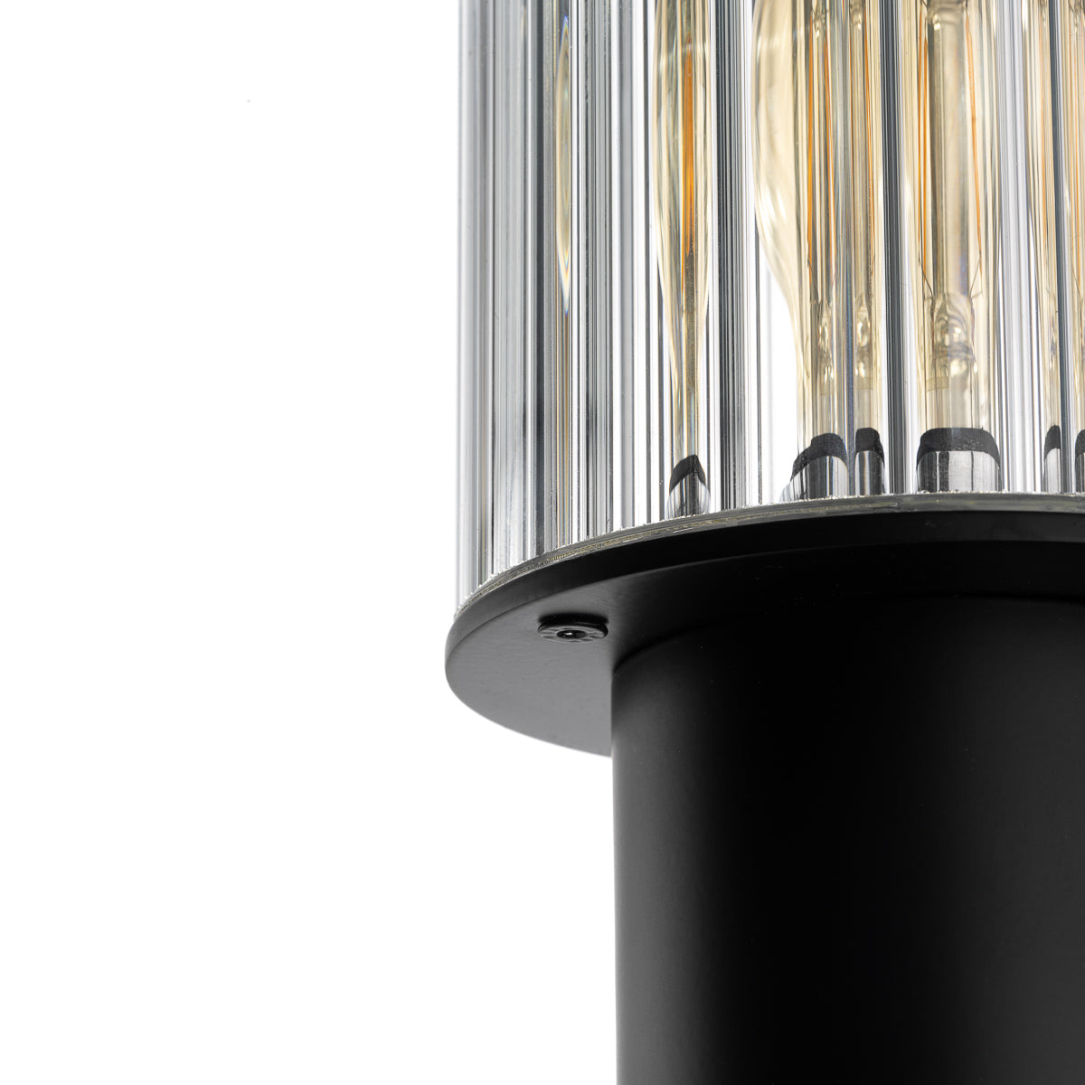 Gros plan sur le diffuseur en verre strié et la bague métallique noire retenant l'ampoule.