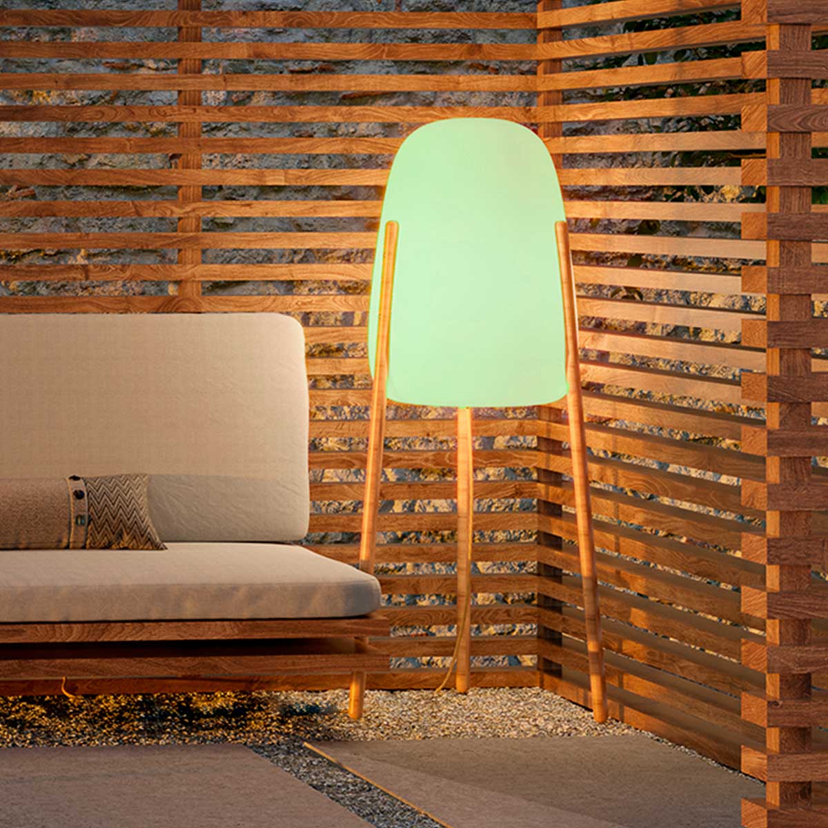 Lampadaire éteint à abat-jour vert translucide devant un claustra en bois ajouré