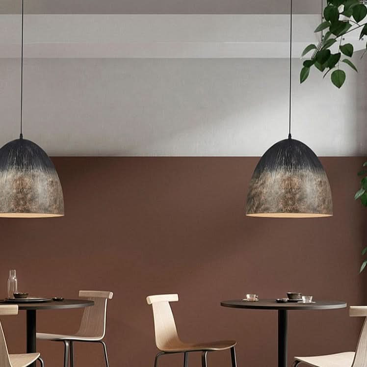 Deux suspensions identiques au-dessus de tables de bistrot dans un décor brun