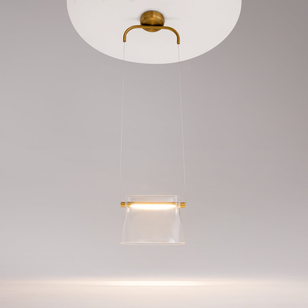Luminaire suspendu allumé sous plafond blanc, verre diffusant une lumière chaude