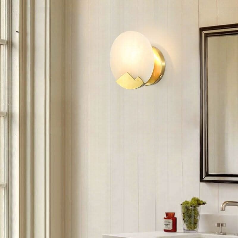 Applique murale ronde en marbre blanc installée près d'un miroir dans une salle de bain.