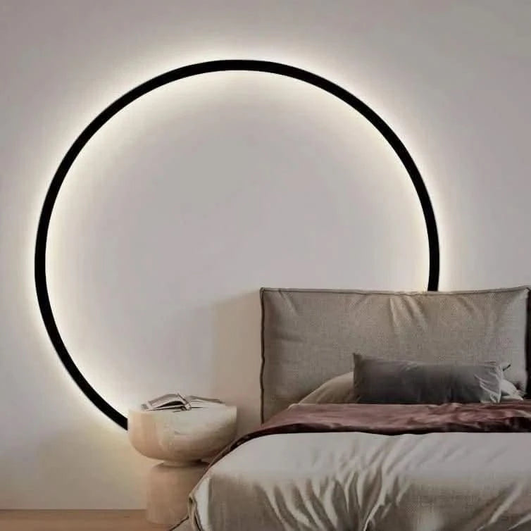 Vue de face sur mur blanc clair, anneau noir et lit beige en lumière chaude