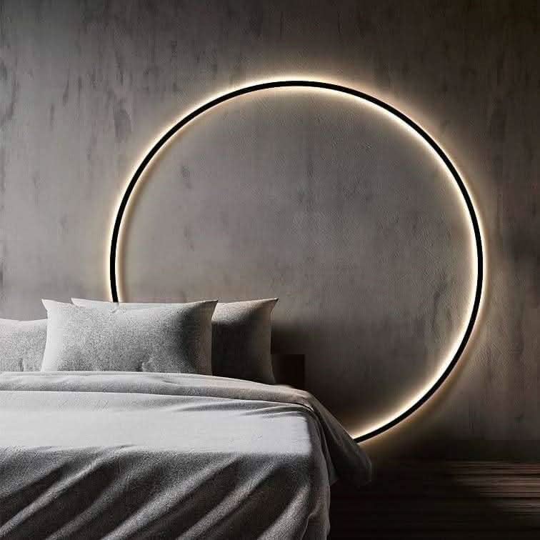 Anneau noir lumineux fixé au-dessus d'un lit gris, ambiance de chambre tamisée