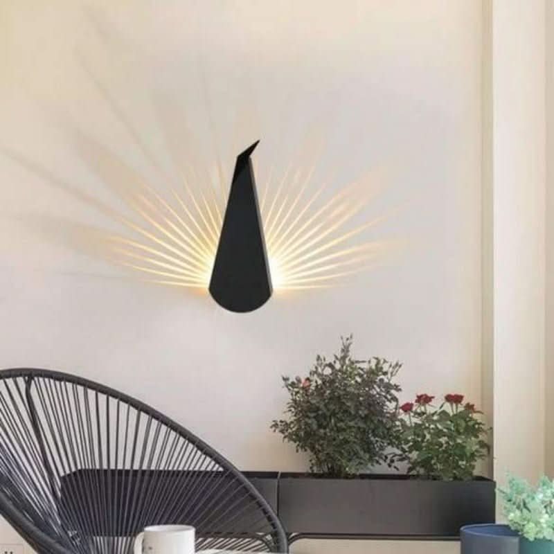 Applique murale noire allumée sur mur beige, fauteuil corde et plantes en pot.