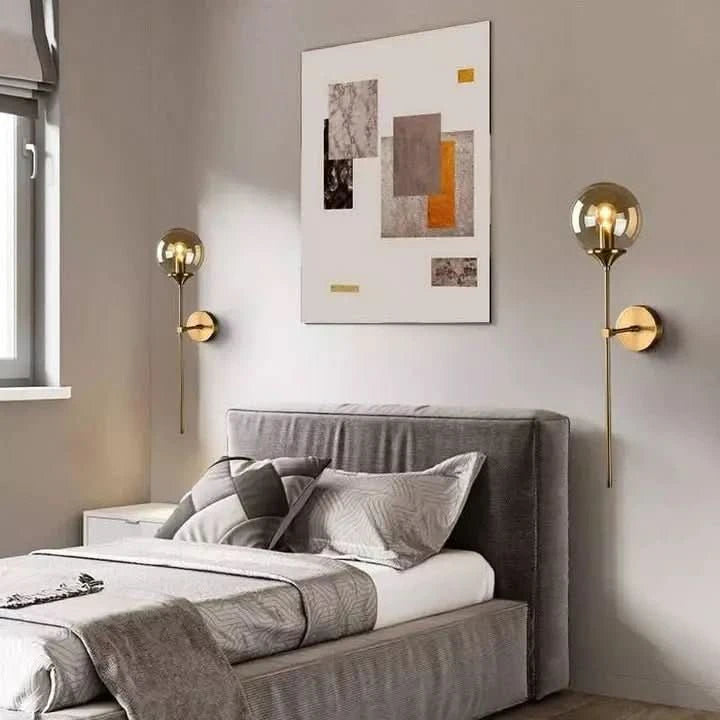 Deux appliques dorées symétriques de part et d'autre d'un lit gris.