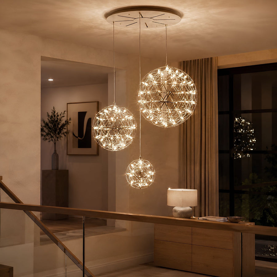 Trois sphères lumineuses de tailles différentes suspendues devant un mur beige dans un salon