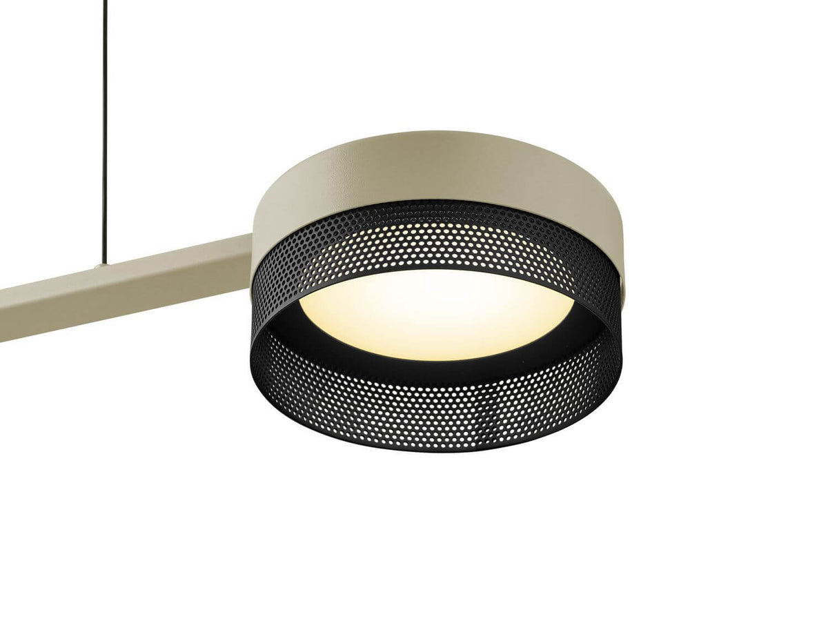 Gros plan sur un abat-jour cylindrique en maille perforée noire et diffuseur blanc allumé.