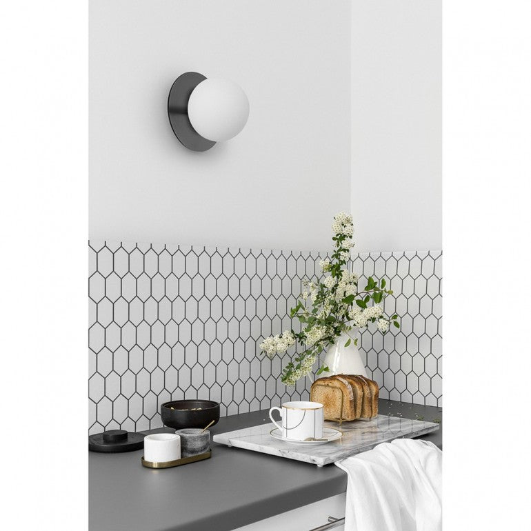 Mise en ambiance dans une cuisine, applique murale noire au-dessus d'un plan de travail.