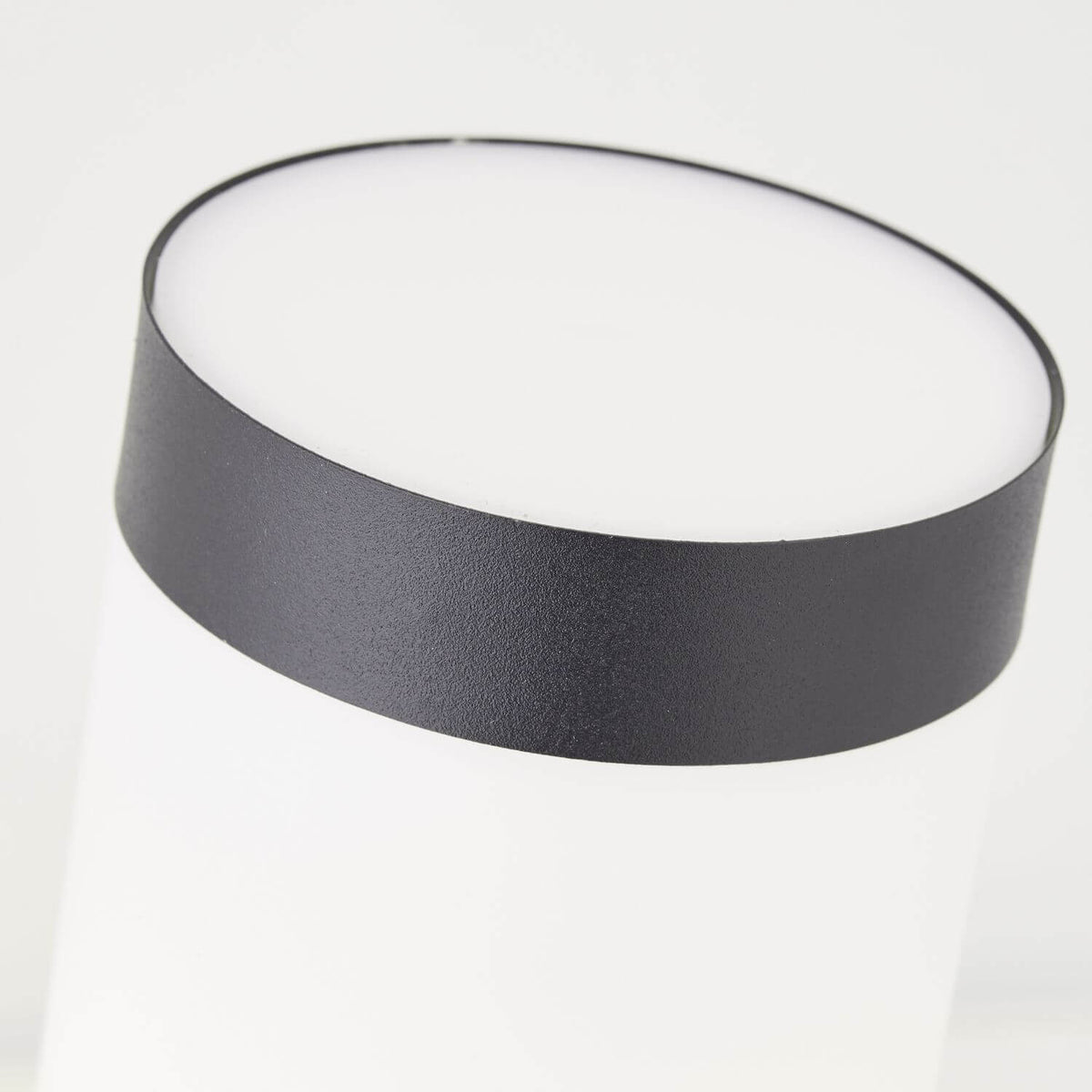 Gros plan sur le bandeau noir supérieur et le bord du diffuseur blanc