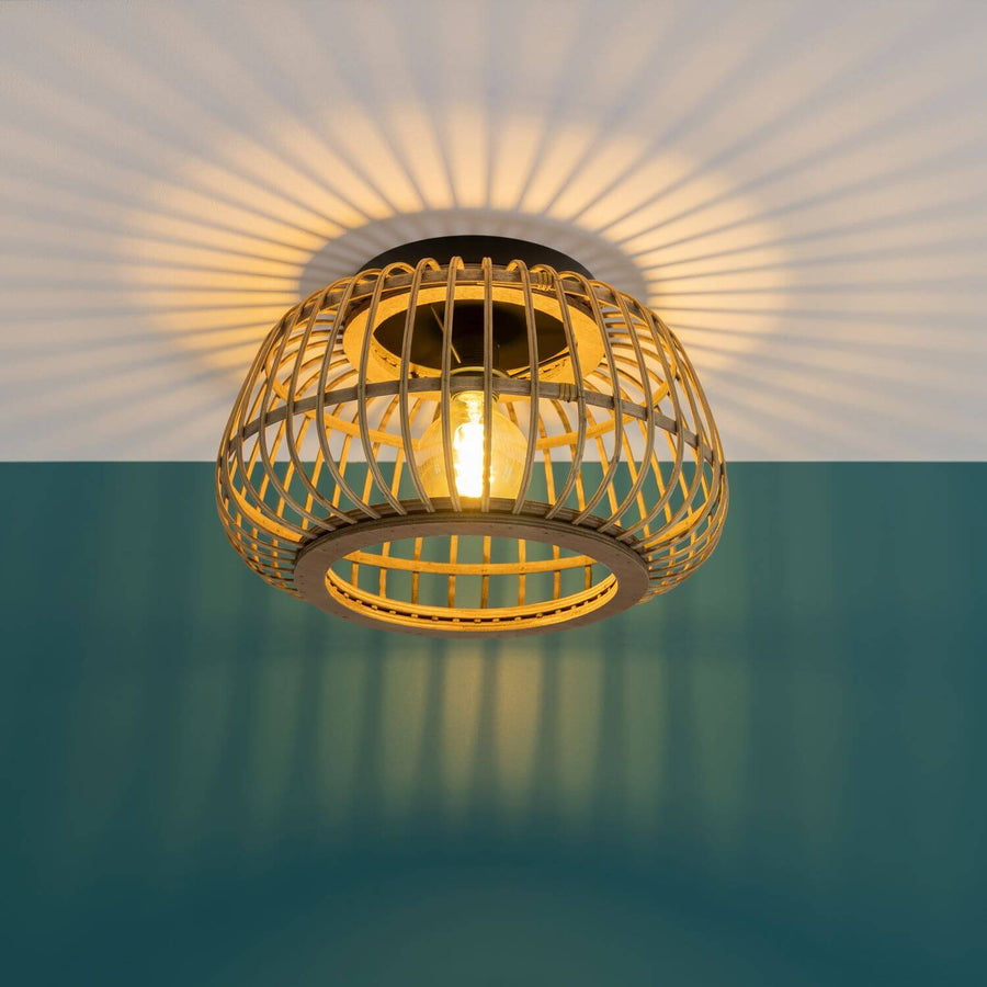 Luminaire allumé projetant des ombres rayonnantes sur plafond blanc et mur bleu canard