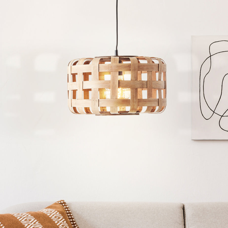Luminaire allumé devant un mur blanc clair, canapé et coussins décorés