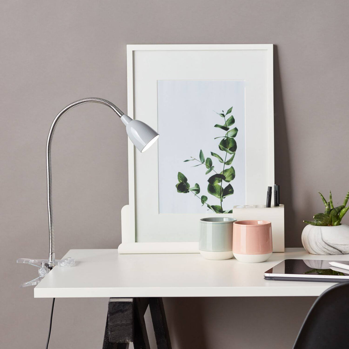 Mise en ambiance sur un bureau blanc avec cadre photo, plantes et tasses pastel