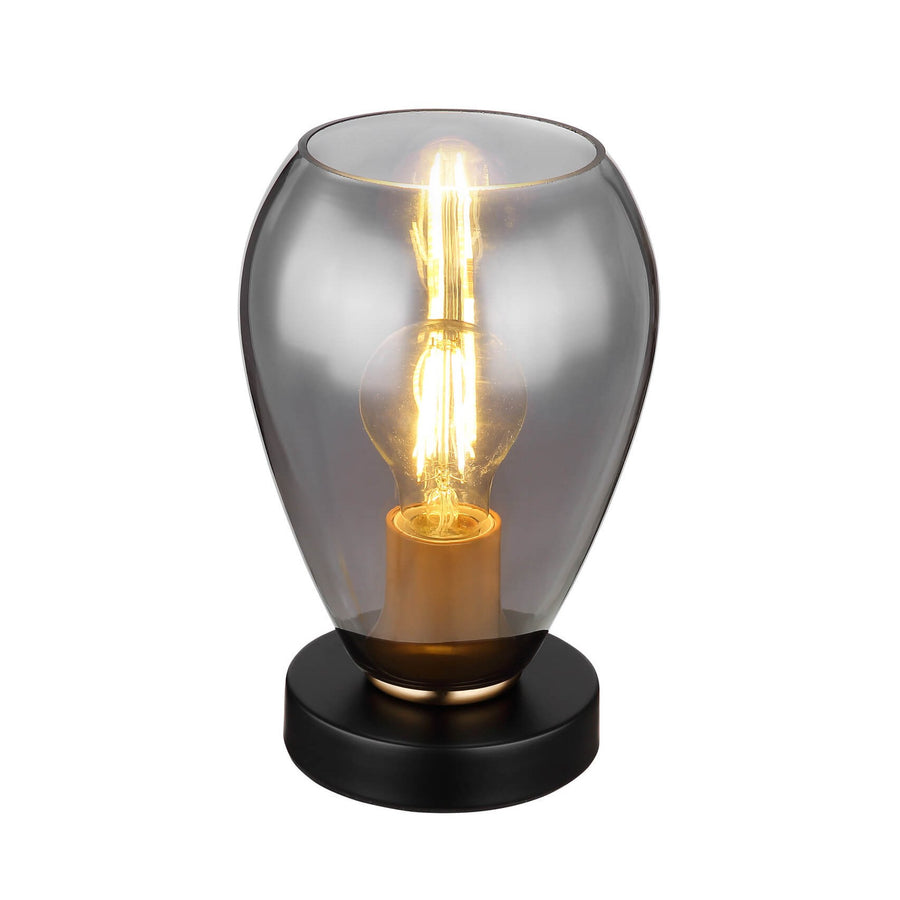 Lampe à poser noire mat, abat-jour en verre fumé et ampoule filament allumée, vue de face.