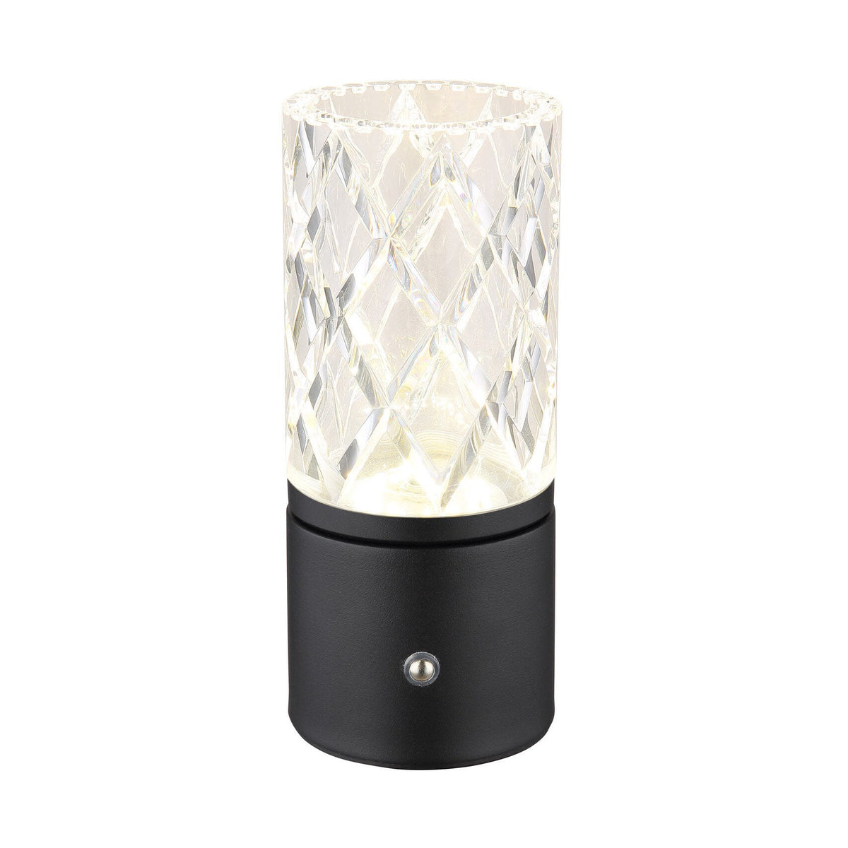 Lampe à poser cylindrique allumée, abat-jour transparent facetté et base noire mate, fond blanc neutre.