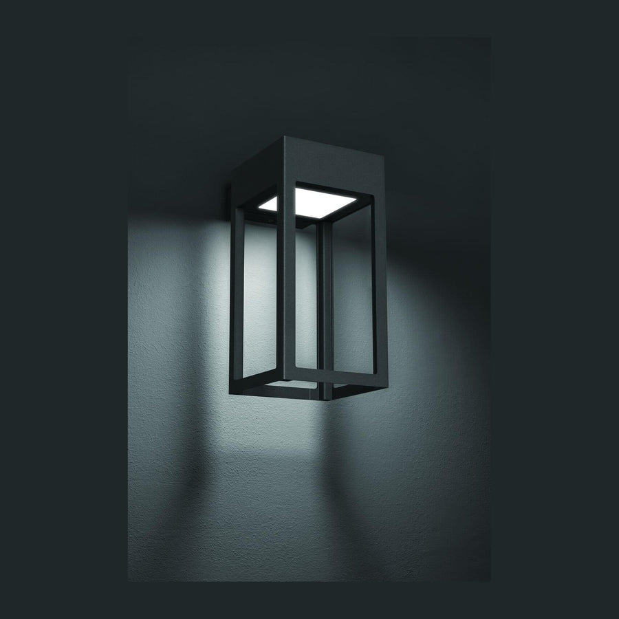 Applique murale extérieure anthracite allumée, halo lumineux diffusé sur un mur sombre
