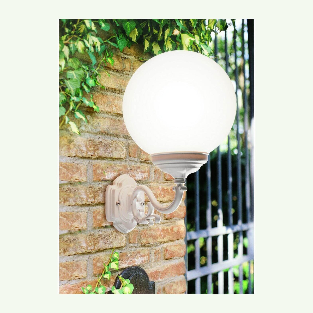 Applique murale blanche avec globe sphérique, bras courbé orné, fixée sur mur de briques.