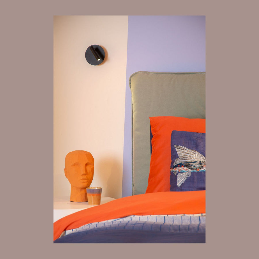 Applique murale noire fixée au-dessus d'une table de chevet dans une chambre colorée