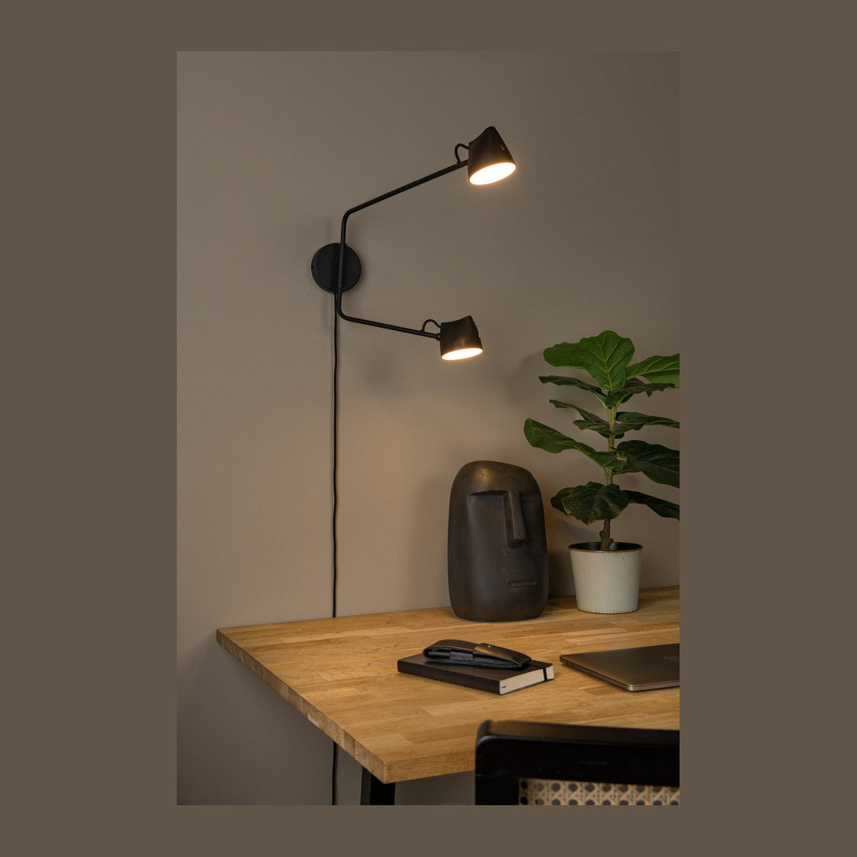 Applique murale noire à deux têtes installée au-dessus d'un bureau en bois clair