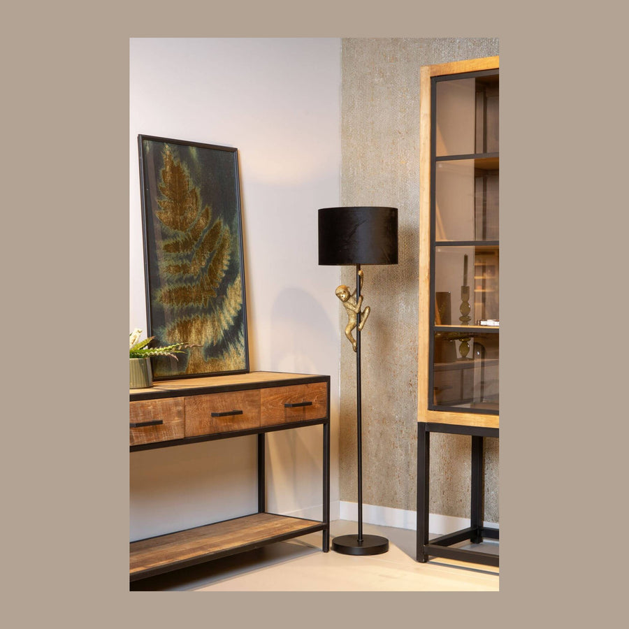 Lampadaire à singe doré et abat-jour noir dans un salon avec console en bois