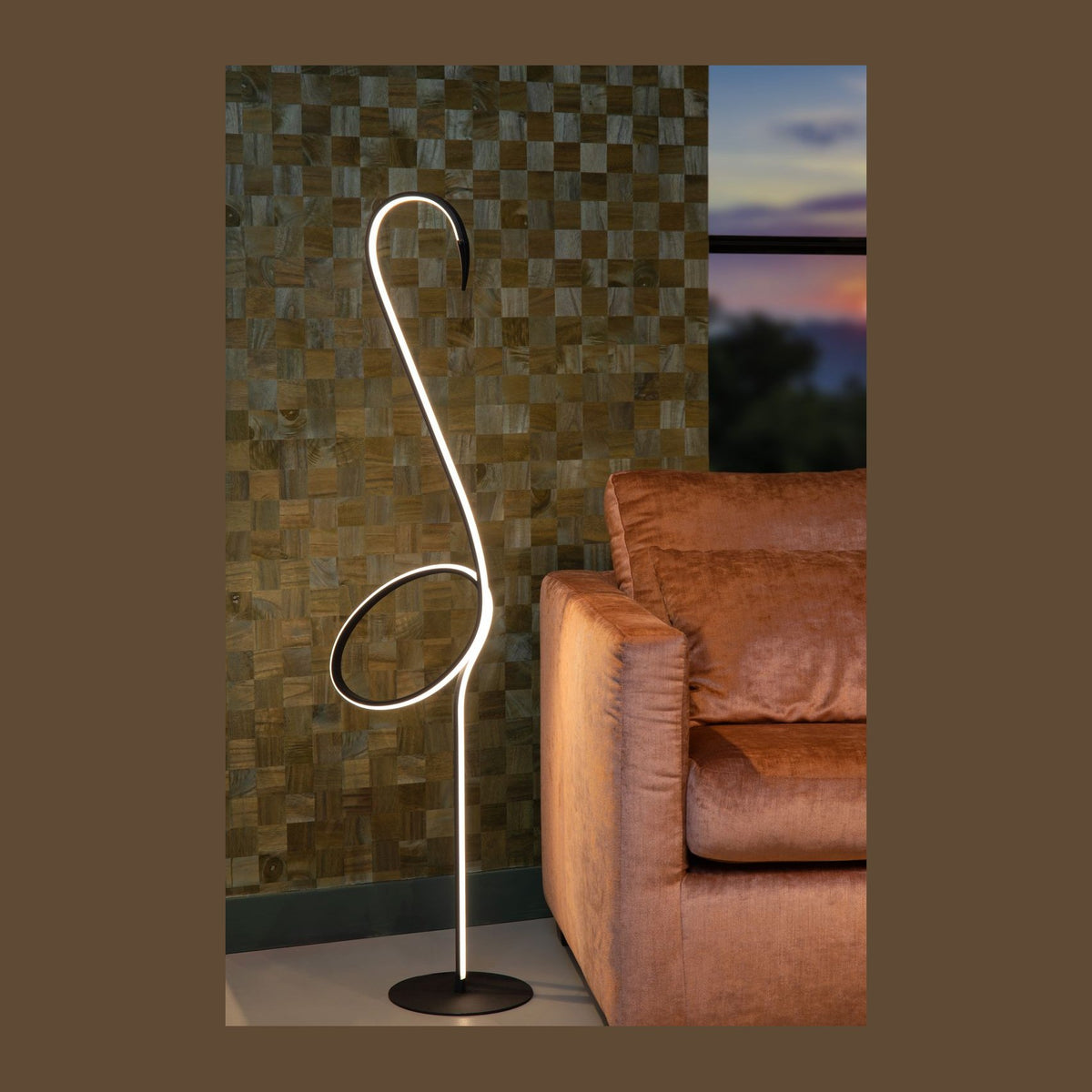 Lampadaire allumé dans un salon, mur en bois quadrillé, canapé orange, fenêtre au crépuscule