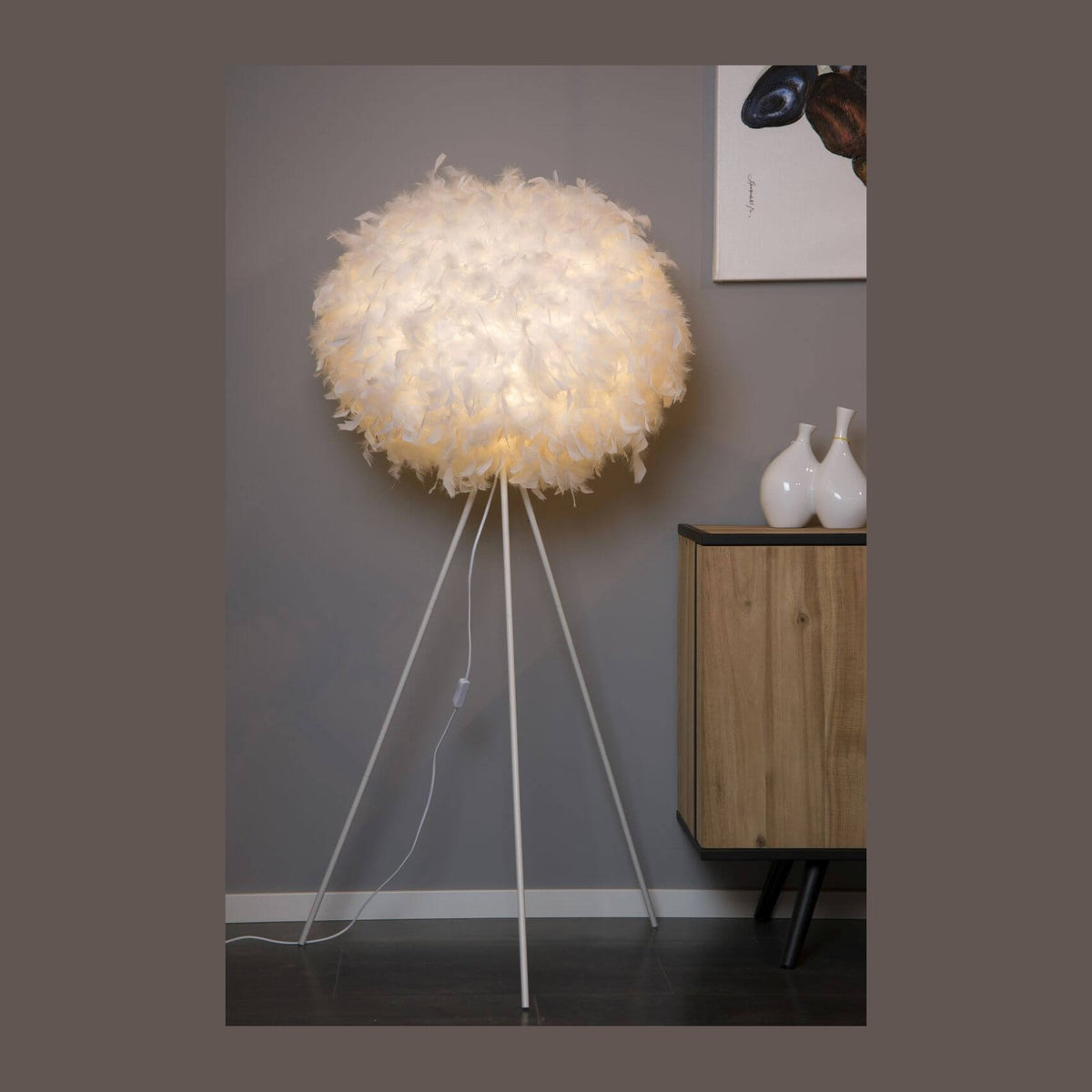 Lampadaire à abat-jour boule en plumes blanches sur pied tripode, dans un intérieur.